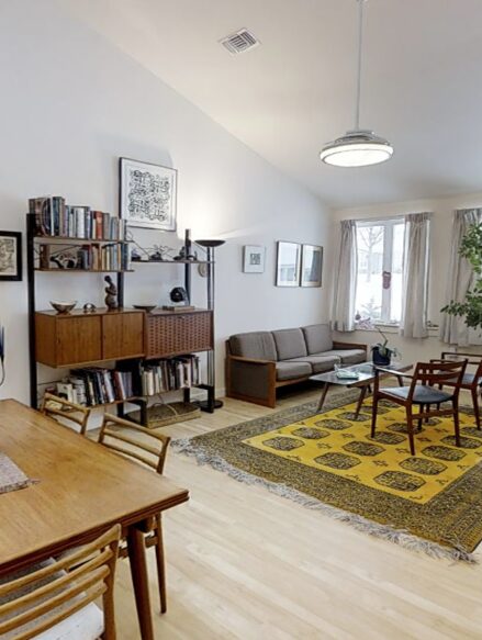 Bright living room with vaulted ceilings viewed from the open concept dining area in a 2 bedroom plus den cottage.